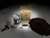 Dark Arts coffee bag, a coffee tumbler with logo, and a large pile of ground coffee with dramatic lighting.