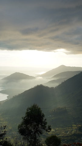 Scenic view of mountains with mist and light breaking through the clouds.